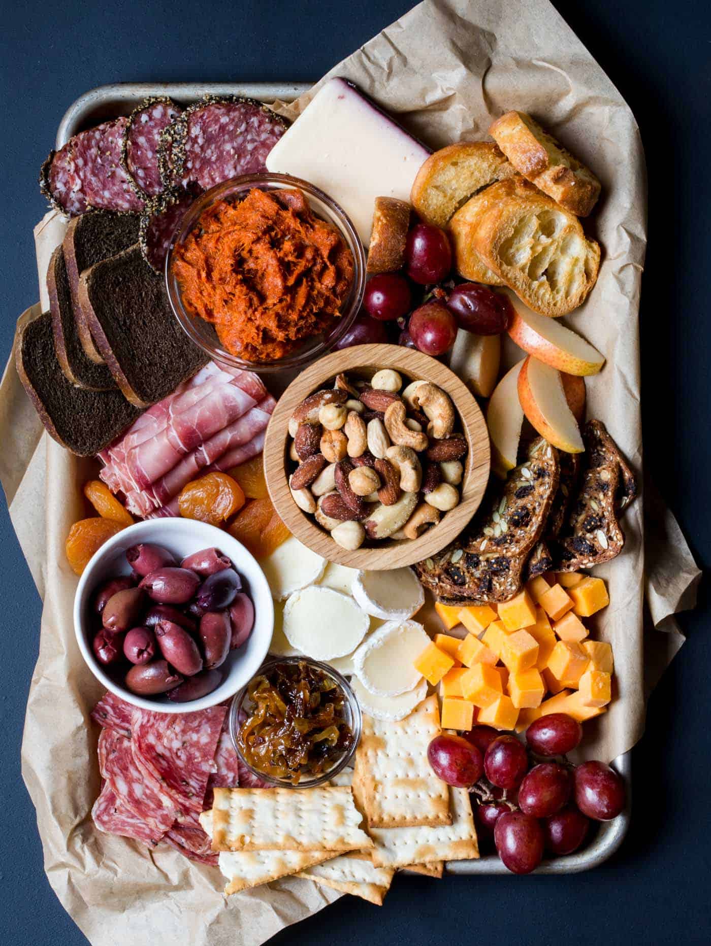meat and cheese tray with olives, grapes, crostini and apples.