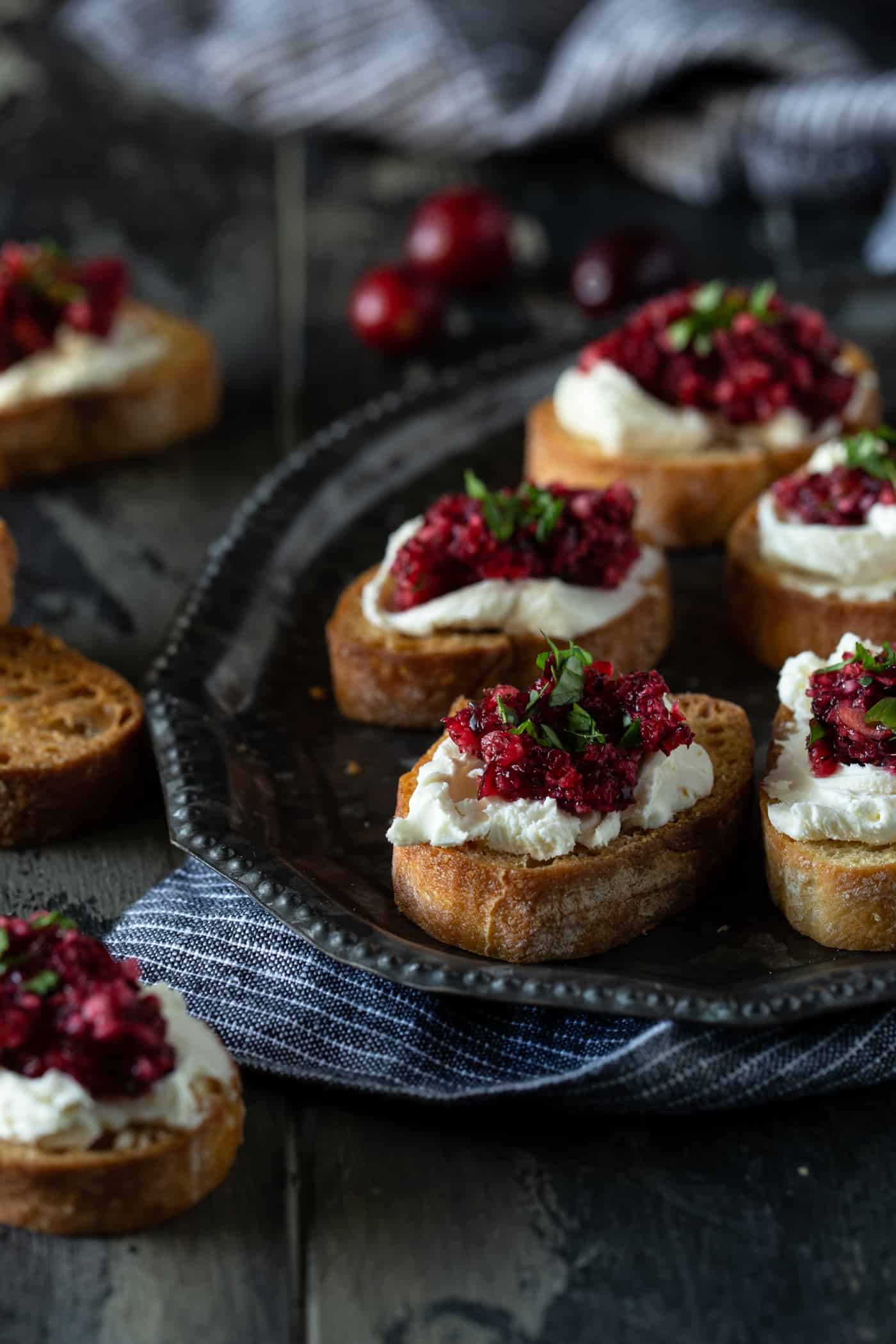 A plate of food with crostini on a table, with Cheese and Cranberry.